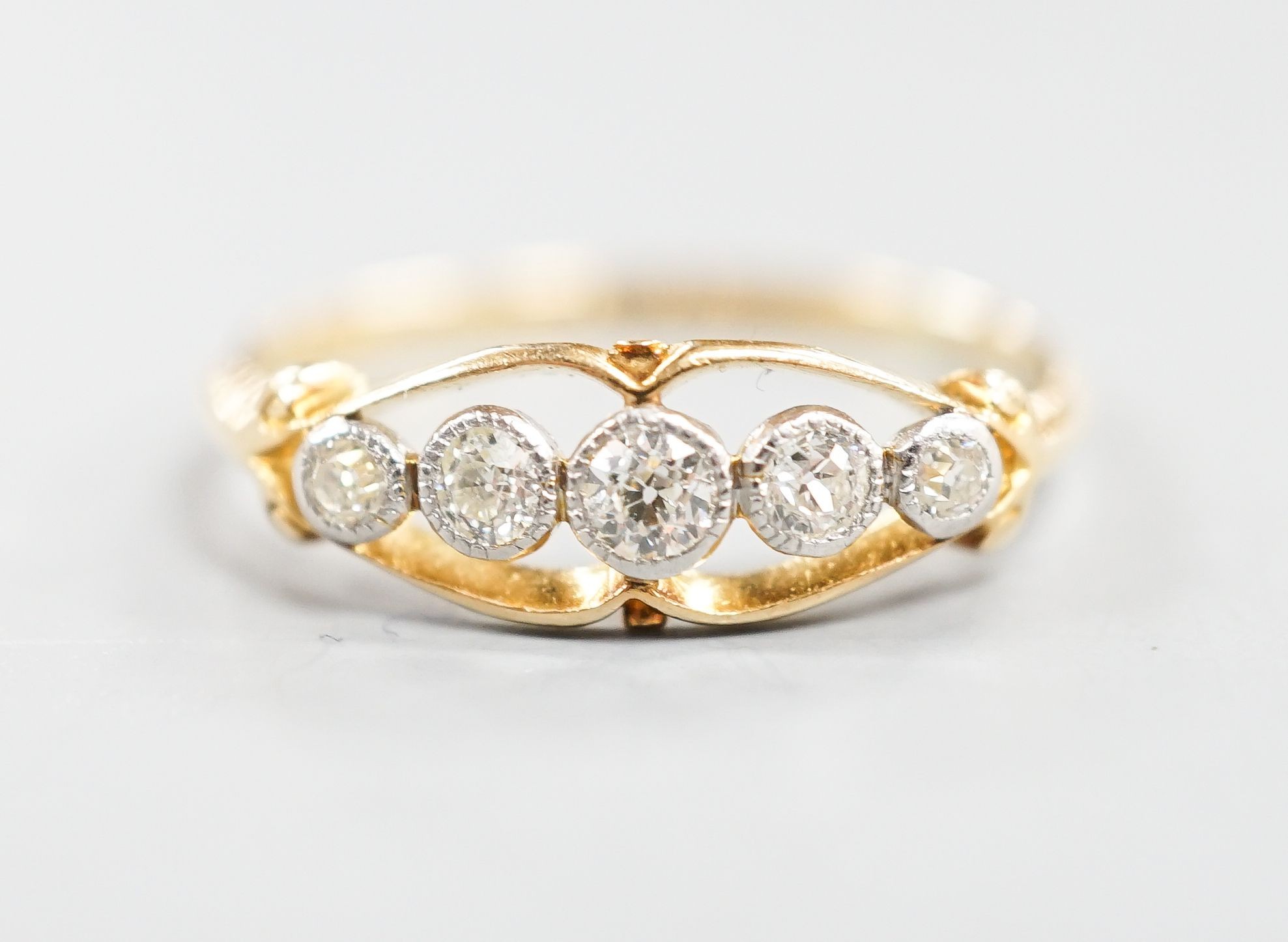 An 18ct and graduated five stone millegrain set diamond ring, size U/W, gross 2.6.